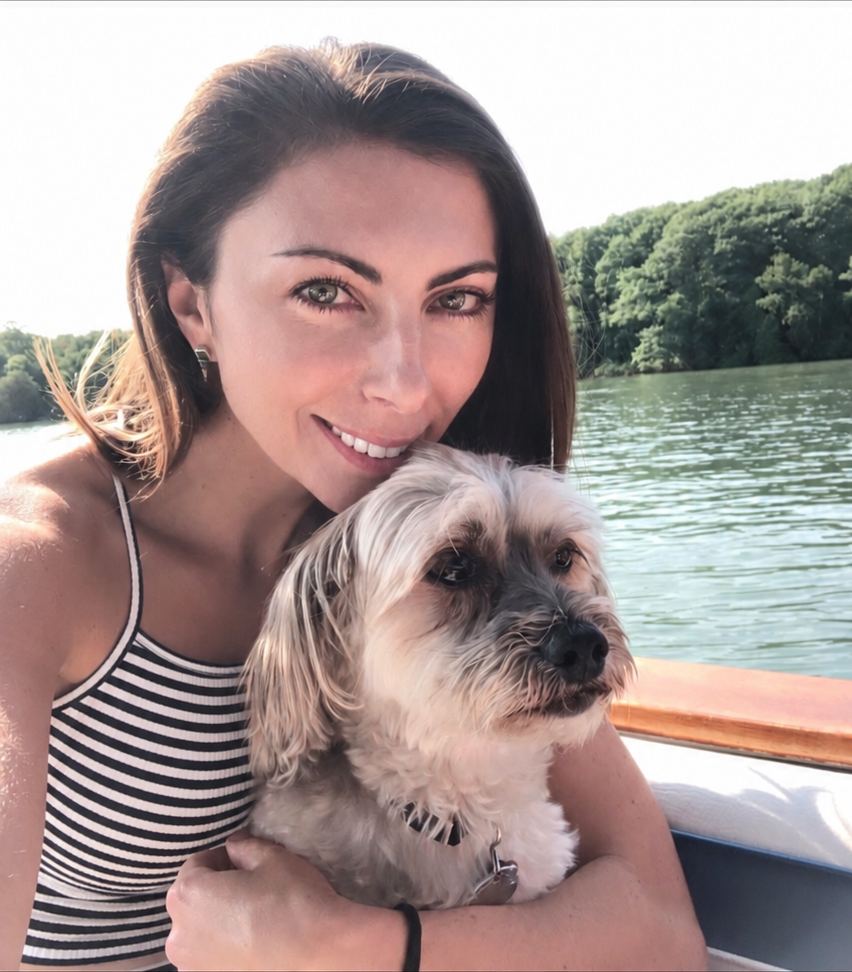 Lisa, owner of Calm Paws Dog Care, cuddling her senior dog Lucy on the water on a sunny day